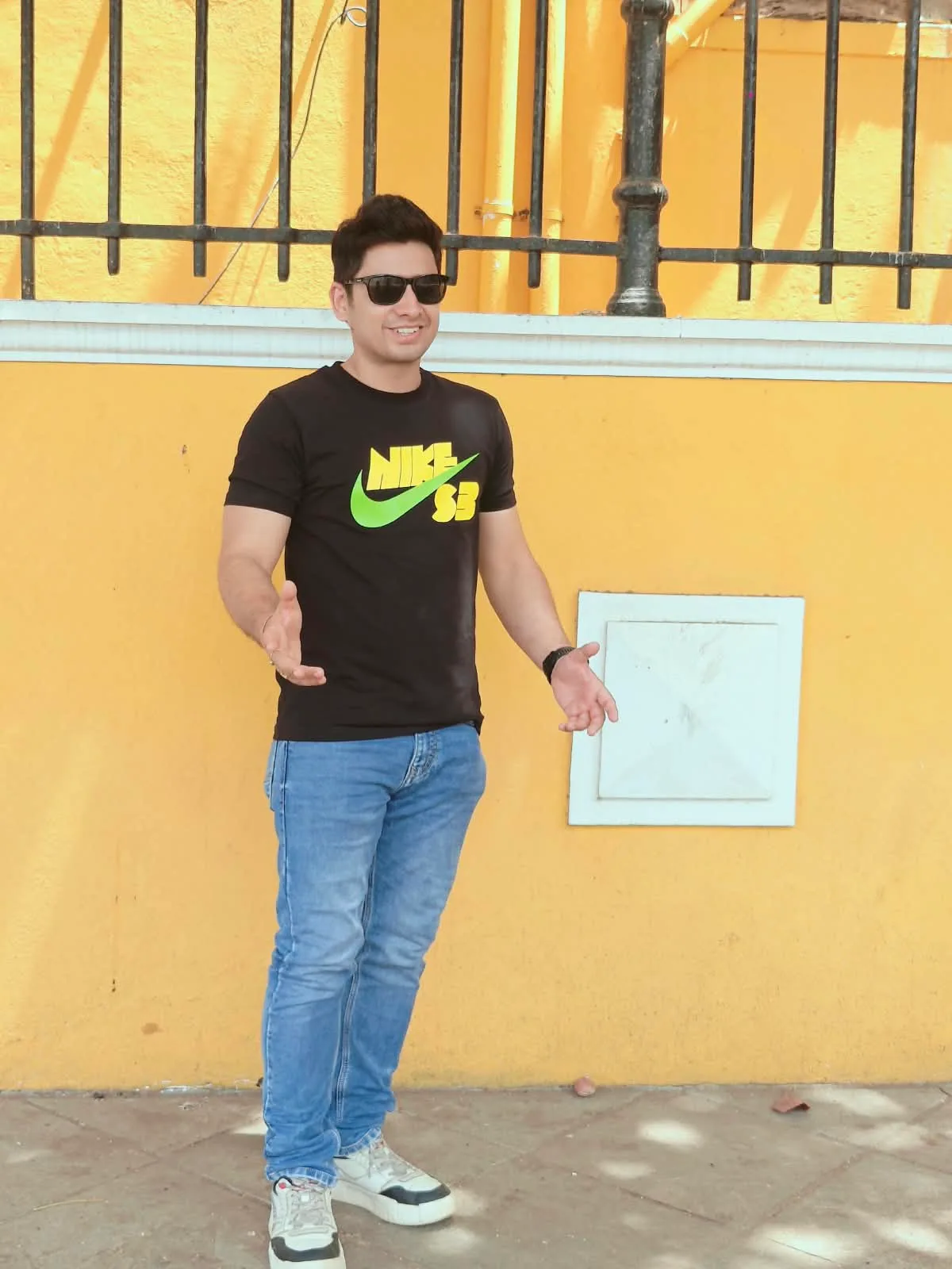 Gaurav smiling outdoors with an open hand gesture